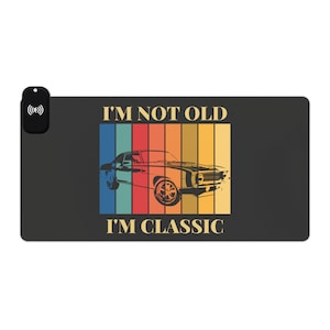 May include: A vintage-style graphic featuring a black silhouette of a classic car and the text "I'm not old I'm classic" in a rainbow colour scheme.