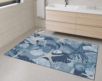 May include: A blue and white bath mat with a seashell and starfish design. The mat is made of a soft, absorbent material and is perfect for adding a touch of coastal style to your bathroom.