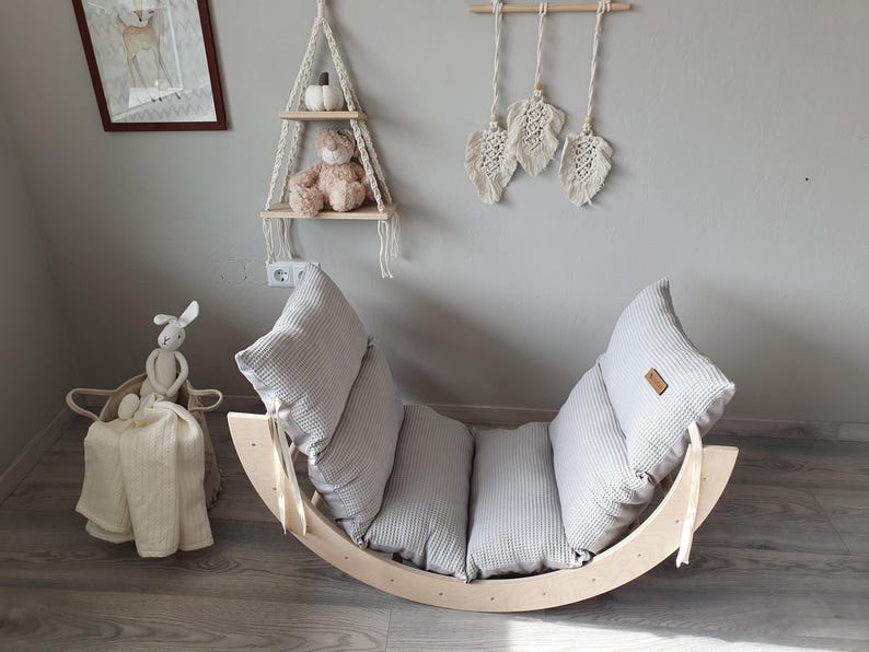 May include: A wooden rocking chair with a gray and white striped cushion. The chair is made of natural wood and has a curved shape. The cushion is made of soft fabric and has a comfortable design.