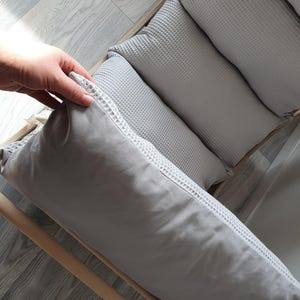 May include: A set of four gray waffle-textured cushions, arranged in a row on a wooden frame. The cushions are soft and comfortable, and would be perfect for a couch or bed.