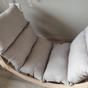 May include: A wooden rocking chair with a gray waffle-textured cushion. The cushion is made up of three separate pieces.