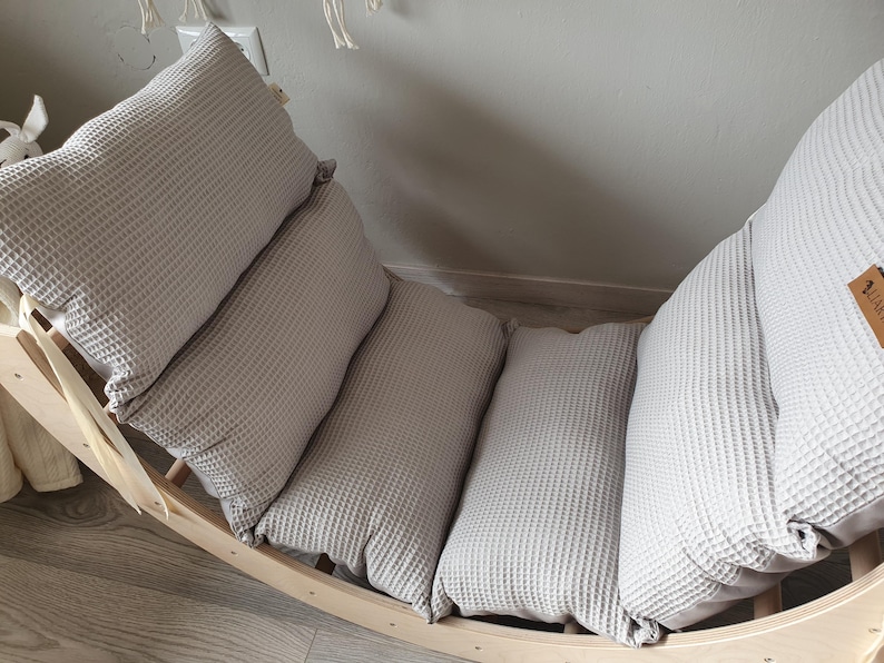 May include: A wooden rocking chair with a gray waffle-textured cushion. The cushion is made up of three separate pieces.