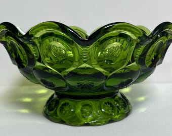 May include: A green glass bowl with a scalloped rim and a pedestal base. The bowl has a textured surface with a pattern of small circles.