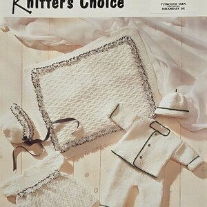 May include: Knitting pattern for a baby blanket, hat, and outfit. The pattern is called "Knitter's Choice" and is made with Plymouth Yarn Dreambaby DK. The blanket is white with a textured stitch and a gray border. The outfit is white with green trim. The hat is white with a green band.