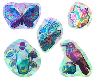 May include: Set of six iridescent holographic stickers featuring a butterfly, a heart, a crystal, a bottle with mushrooms, a crow, and a skull. The stickers are all in a rainbow color scheme.