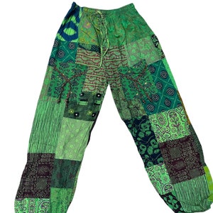 May include: Green patchwork trousers with a drawstring waist. The trousers are made from different fabrics with various patterns, including paisley, floral, and geometric designs.