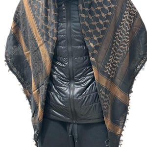 May include: A black and brown patterned scarf with a geometric design. The scarf has brown stripes and tassels at the ends. The scarf is draped over a black jacket.