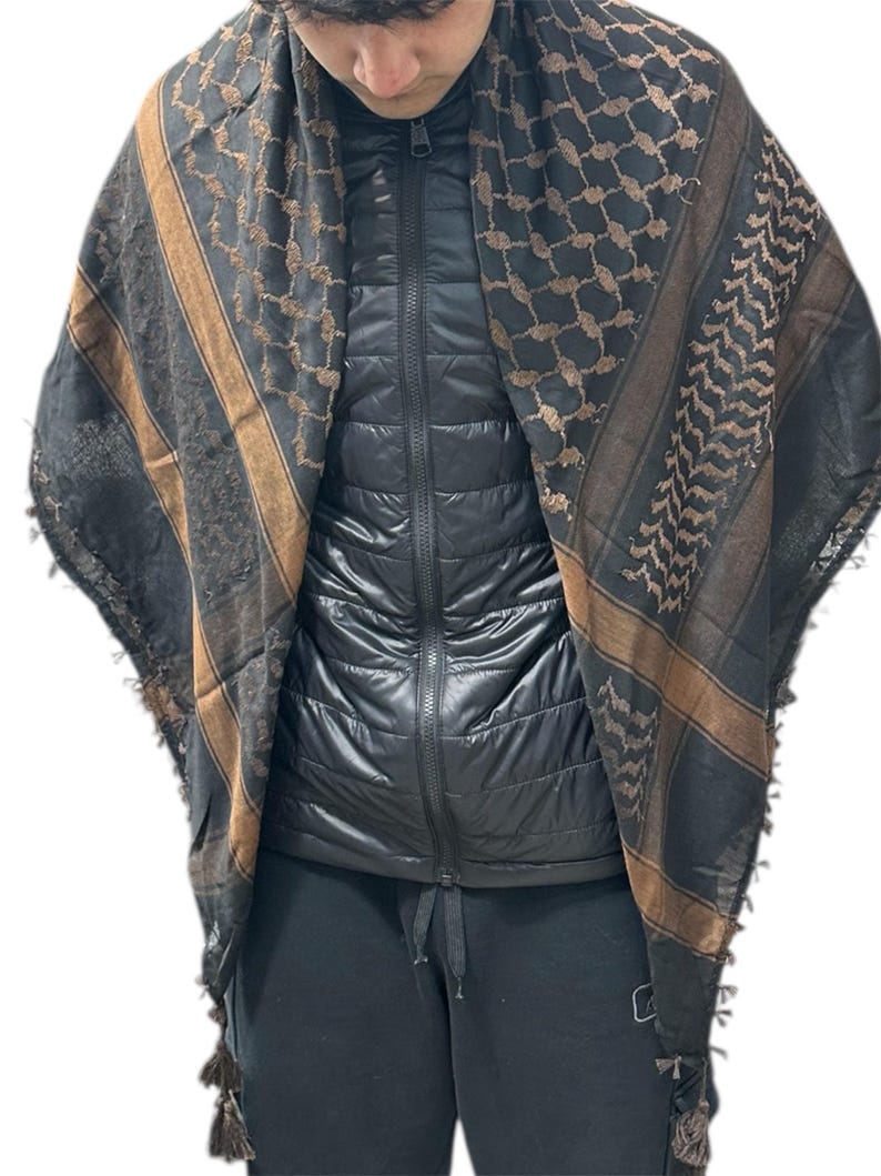 May include: A black and brown patterned scarf with a geometric design. The scarf has brown stripes and tassels at the ends. The scarf is draped over a black jacket.
