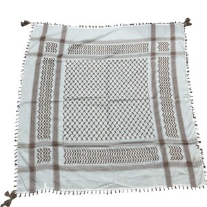 May include: A square, off-white scarf with a brown geometric pattern and fringe. The scarf features a repeating diamond and zigzag design, with brown stripes along the edges and tassels at each corner. The scarf is made of a soft, lightweight material.
