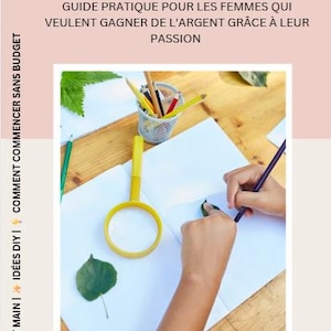May include: A book cover with the title "Artisanat qui se vend" and French text. The image shows hands drawing on paper with a pencil, a yellow magnifying glass, and a small metal container of colored pencils.