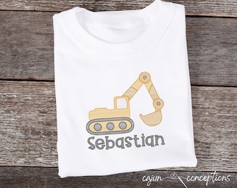 May include: White t-shirt with an embroidered yellow excavator and the name Sebastian in gray.