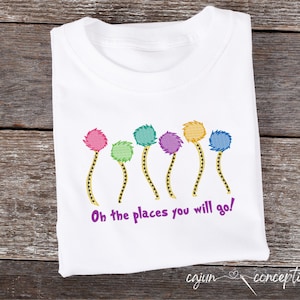 May include: White t-shirt with a colourful embroidered design of six Truffula Trees from the book "Oh, the Places You'll Go!" by Dr. Seuss. The text "Oh the places you will go!" is also embroidered on the shirt.