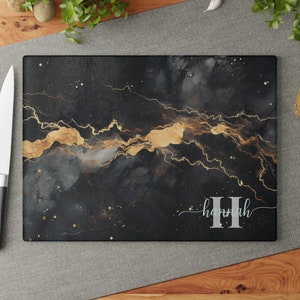May include: Black and gold marble-patterned cutting board with the name "Hannah" in silver lettering.