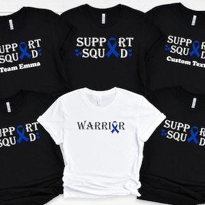 May include: Five black t-shirts with blue ribbon designs. One white t-shirt with a blue ribbon design and the word "WARRIOR". The shirts have the text "SUPPORT SQUAD" with a blue ribbon and hearts. One shirt has the text "Team Emma". Another shirt has the text "Custom Text".