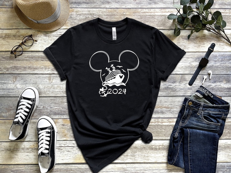 Op de afbeelding: Zwart T-shirt met een wit Mickey Mouse-kopontwerp met een cruiseschip in de oren en de tekst "2024" eronder.
