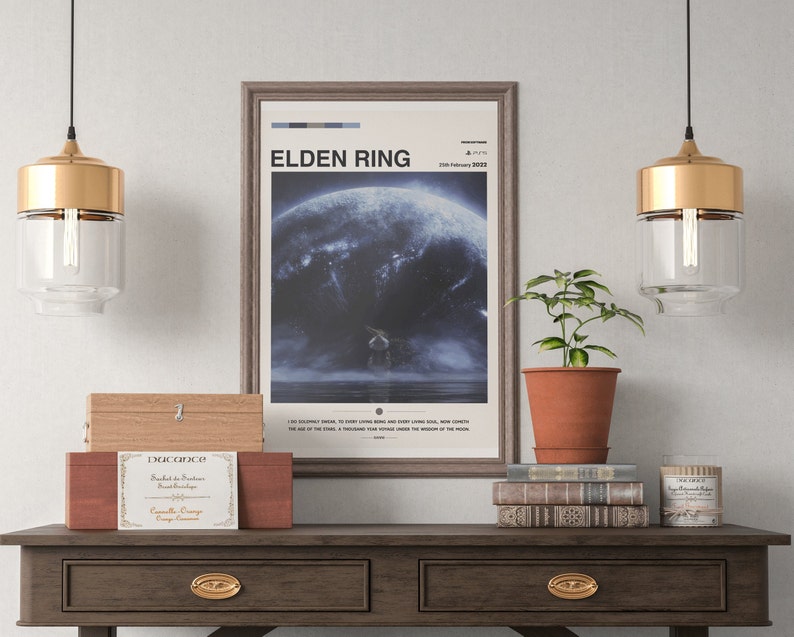 May include: A framed poster with the title "ELDEN RING" and a blue and white image of a character standing on a cliff overlooking a stormy sea. The poster is hanging on a white wall above a wooden table with a wooden box, a potted plant, a stack of books, and a candle.