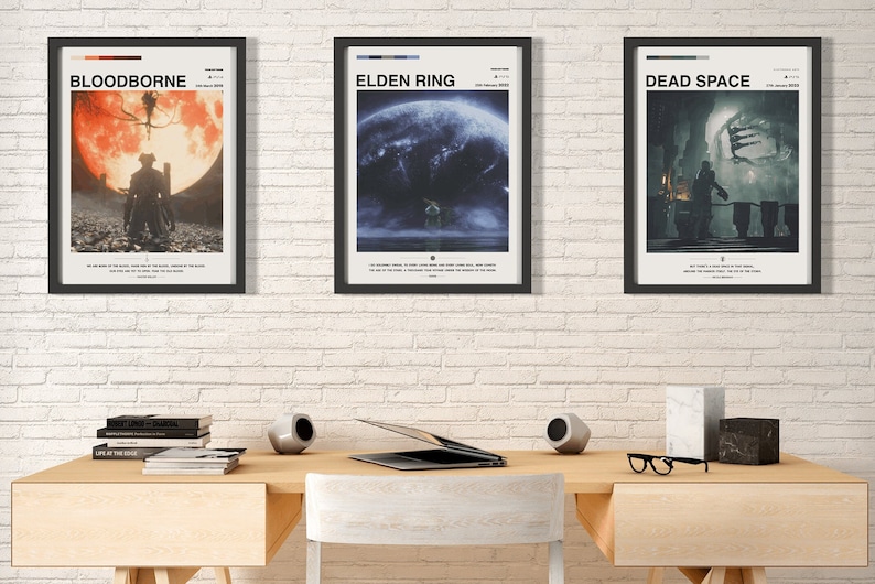 May include: Three framed posters on a white brick wall. The posters are for the video games Bloodborne, Elden Ring, and Dead Space. The posters are all in a minimalist style with black frames and white text.