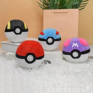 May include: Four plush Poké Balls in various colors: red, black, blue, and purple. Each ball has a white base, a black band, and a central white circle. The purple ball features a white "W" on top.