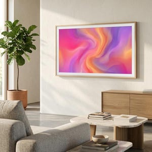 May include: A rectangular television screen mounted on a wall, displaying a vibrant abstract digital artwork with swirling gradients of hot pink, bright orange, and soft purple. The screen is encased in a light-colored wooden frame.