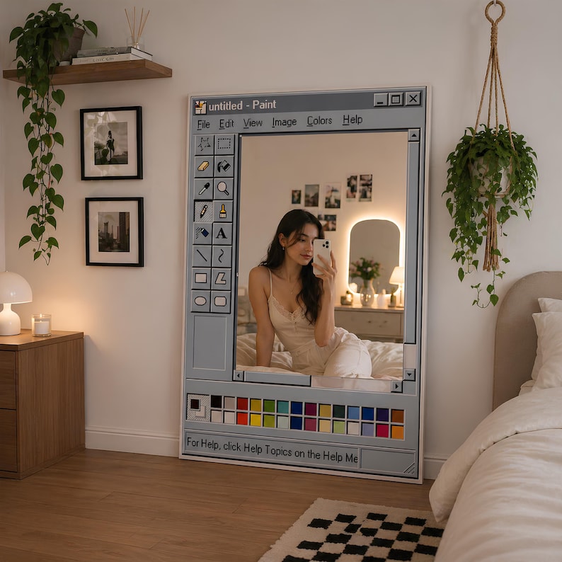 Op de afbeelding: Een grote, rechthoekige spiegel ontworpen om te lijken op een klassieke computer paint programma-interface. Het grijze frame heeft een werkbalk met pictogrammen en een kleurenpalet. De tekst "untitled - Paint" staat bovenaan. De spiegel reflecteert een slaapkamer.