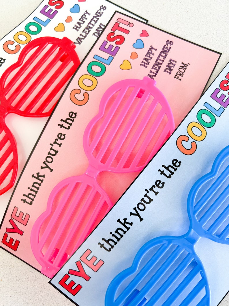 K&ouml;nnte beinhalten: Drei Valentinstagskarten mit herzf&ouml;rmigen Sonnenbrillen. Die Karten sind rosa, blau und rot. Jede Karte sagt "EVE think you're the COOLEST!" mit Herzen und dem Text "Happy Valentine's Day" oben.