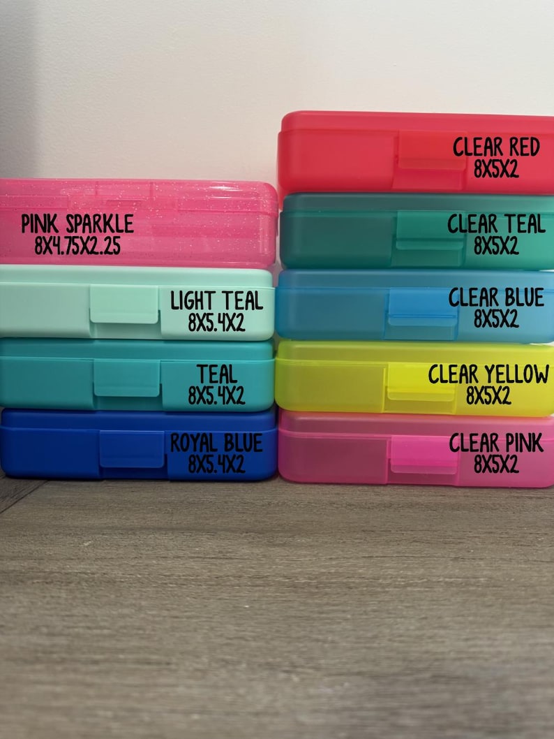 K&ouml;nnte beinhalten: Eine Sammlung von neun rechteckigen Kunststoff-Etuis, die in zwei Spalten gestapelt sind. Die Etuis sind mit ihren Farben und Abmessungen in Zoll beschriftet: Pink Sparkle 8x4.75x2.25, Light Teal, Teal, Royal Blue, Clear Red, Clear Teal, Clear Blue, Clear Yellow und Clear Pink 8x5x2.