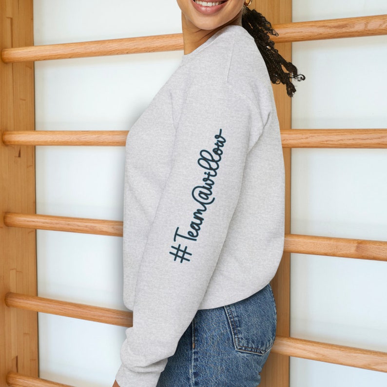 May include: A gray sweatshirt with long sleeves and a crew neck. The left sleeve has the text "#TeamAwillow" printed on it in black.