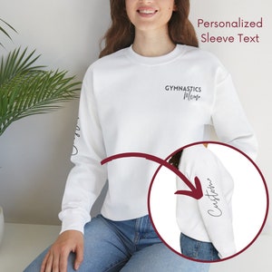 May include: White long-sleeve sweatshirt with the text "Gymnastics Mom" on the front and the word "Custom" on the left sleeve.