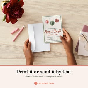 May include: A rectangular Christmas party invitation card featuring three hanging ornaments in red and green, with the text Merry & Bright Christmas Party, date, time, and location details, held alongside a plain white envelope on a wooden surface.