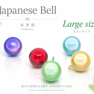 May include: Five spherical Japanese bells, or Suikinsuzu, in purple, red, light blue, green, and gold. The text reads Japanese Bell, Large sizes, Suikinsuzu, and A clear, soothing sound that heals the heart. Each bell has a smooth, metallic finish.