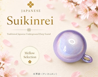 May include: A spherical purple bell with a small loop attachment. The text reads: JAPANESE Suikinrei, Traditional Japanese Underground Harp Sound, Mellow Selection, 水琴鈴 (すいきんれい), MADE IN JAPAN. Pink cherry blossom flowers surround the bell.