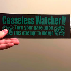 Puede incluir: Una pegatina rectangular negra con el texto verde "Ceaseless Watcher!! Turn your gaze upon this attempt to merge". La pegatina presenta dise&ntilde;os de ojos verdes a cada lado del texto.