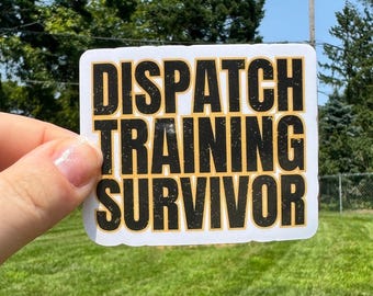 May include: A white sticker with black text that reads "DISPATCH TRAINING SURVIVOR". The text is in a bold, blocky font and has a distressed look.