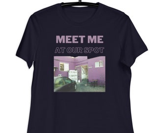 Può includere: Una t-shirt blu navy con il testo "MEET ME AT OUR SPOT" in un colore lilla chiaro. La t-shirt presenta una grafica di un edificio viola con un'auto parcheggiata di fronte.