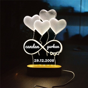 Könnte beinhalten: Weißes LED-Nachtlicht mit einem Design aus vier Herzen und einem Unendlichkeitszeichen mit den Namen "candan" und "gurkan" sowie dem Datum "29.12.2008".