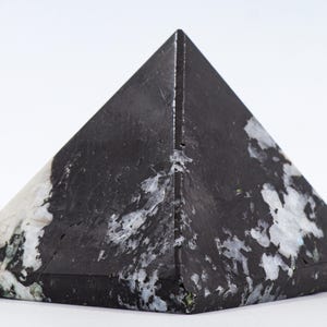 以下が含まれることがあります： 黒と白のピラミッド型の装飾品。ピラミッドは、黒と白の模様が混ざり合った、滑らかで光沢のある表面を持っています。ピラミッドはしっかりとした幾何学的な形で、色はオブジェクト全体に分布しています。