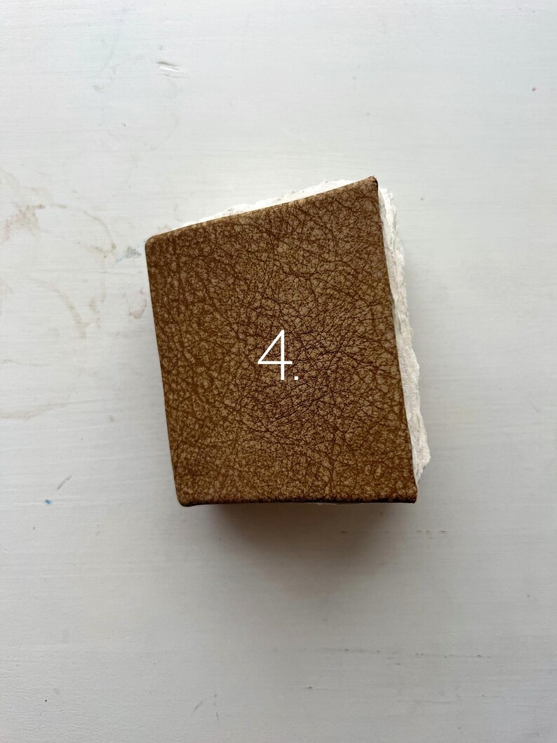 May include: A rectangular object with a brown, textured surface and the number "4" in white. The object has a rough, white edge on one side. The item is likely a decorative piece or a small box.
