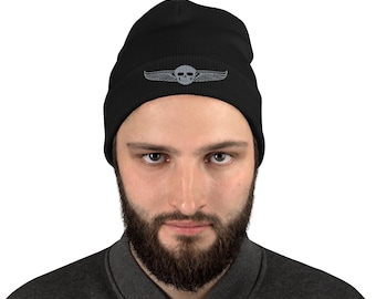 Puede incluir: Gorro negro con un diseño de calavera y alas grises. El gorro está hecho de un material suave y cómodo y es perfecto para mantener la cabeza caliente en invierno.