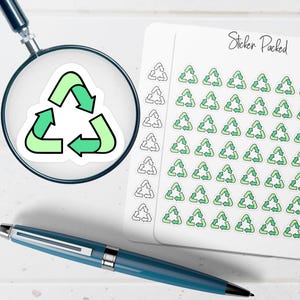 May include: A white sticker with a green recycle symbol is magnified by a magnifying glass. A sheet of stickers with multiple recycle symbols is next to the magnifying glass. A blue pen is in the foreground. The text "Sticker Packed" is on the sheet of stickers.