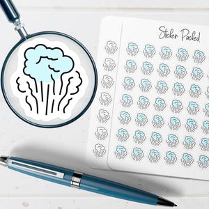 May include: A sheet of small stickers featuring a light blue cloud graphic with black outlines, labeled Sticker Packed at the top. A magnifying glass shows one sticker in detail, and a dark blue pen lies horizontally below the sticker sheet.