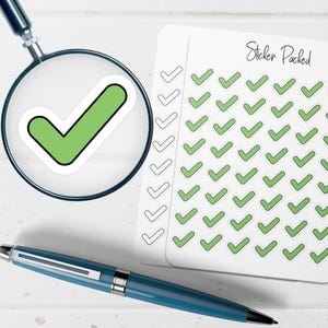 May include: A sheet of white planner stickers featuring rows of green checkmark icons and the text Sticker Packed, with a magnifying glass focusing on a single green checkmark sticker and a blue metal ballpoint pen positioned below.