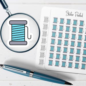May include: A sticker sheet with multiple teal and gray spool stickers, and a single spool sticker magnified by a magnifying glass. A blue pen is in the foreground. The sticker sheet has the text "Sticker Packed".