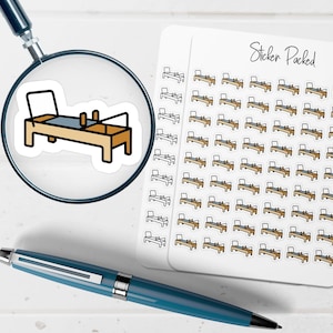 May include: A sticker sheet with multiple Pilates reformer stickers. The stickers are of a Pilates reformer with a tan frame, a blue mat, and black accents. The stickers are arranged on a white background. The words "Sticker Packed" are written in cursive.