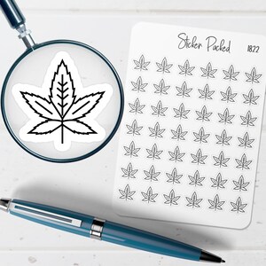 May include: A sheet of white stickers featuring a black cannabis leaf design. The stickers are arranged in rows and columns. A magnifying glass shows a close-up of a single sticker. A blue pen is in the foreground. The text "Sticker Packed 1822" is on the sheet.