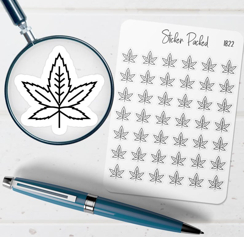 May include: A sheet of white stickers featuring a black cannabis leaf design. The stickers are arranged in rows and columns. A magnifying glass shows a close-up of a single sticker. A blue pen is in the foreground. The text "Sticker Packed 1822" is on the sheet.