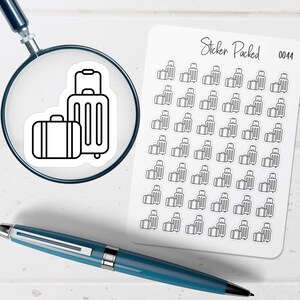 May include: A sheet of travel-themed stickers with a repeating pattern of suitcases. A magnifying glass focuses on a sticker with two suitcases. The text "Sticker Packed 0044" is visible. A blue pen rests on the white surface.