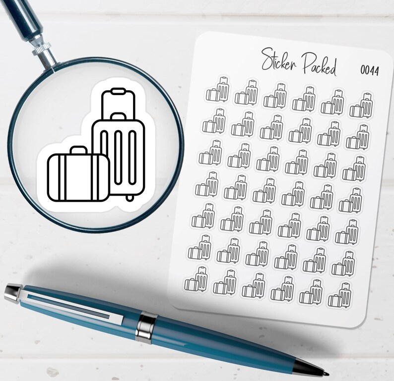 May include: A sheet of travel-themed stickers with a repeating pattern of suitcases. A magnifying glass focuses on a sticker with two suitcases. The text "Sticker Packed 0044" is visible. A blue pen rests on the white surface.
