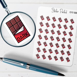 K&ouml;nnte beinhalten: Ein Bogen Aufkleber mit einem Design einer dunklen Schokoladentafel mit roter Verpackung und dem Wort "DARK". Die Aufkleber sind auf wei&szlig;em Hintergrund angeordnet. Eine Lupe und ein blauer Stift sind ebenfalls im Bild.