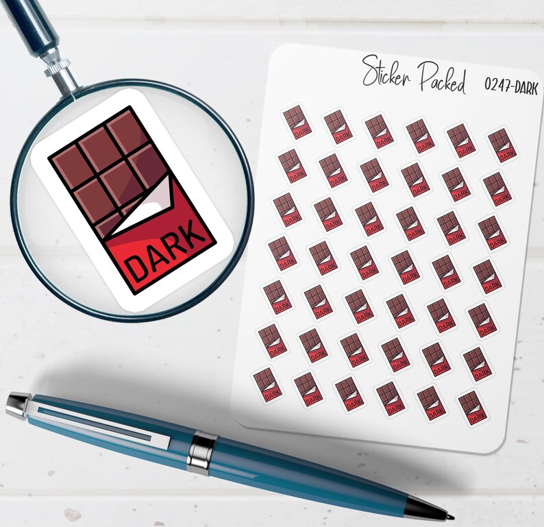 K&ouml;nnte beinhalten: Ein Bogen Aufkleber mit einem Design einer dunklen Schokoladentafel mit roter Verpackung und dem Wort "DARK". Die Aufkleber sind auf wei&szlig;em Hintergrund angeordnet. Eine Lupe und ein blauer Stift sind ebenfalls im Bild.