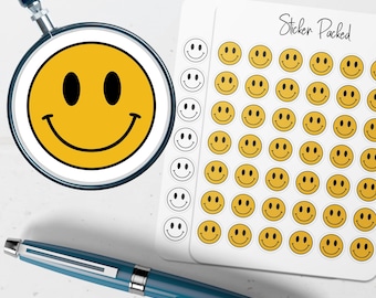 May include: A yellow smiley face sticker is magnified by a magnifying glass. A sheet of stickers with multiple yellow smiley faces is next to the magnifying glass. A blue pen is in the foreground. The sheet of stickers has the text "Sticker Packed".